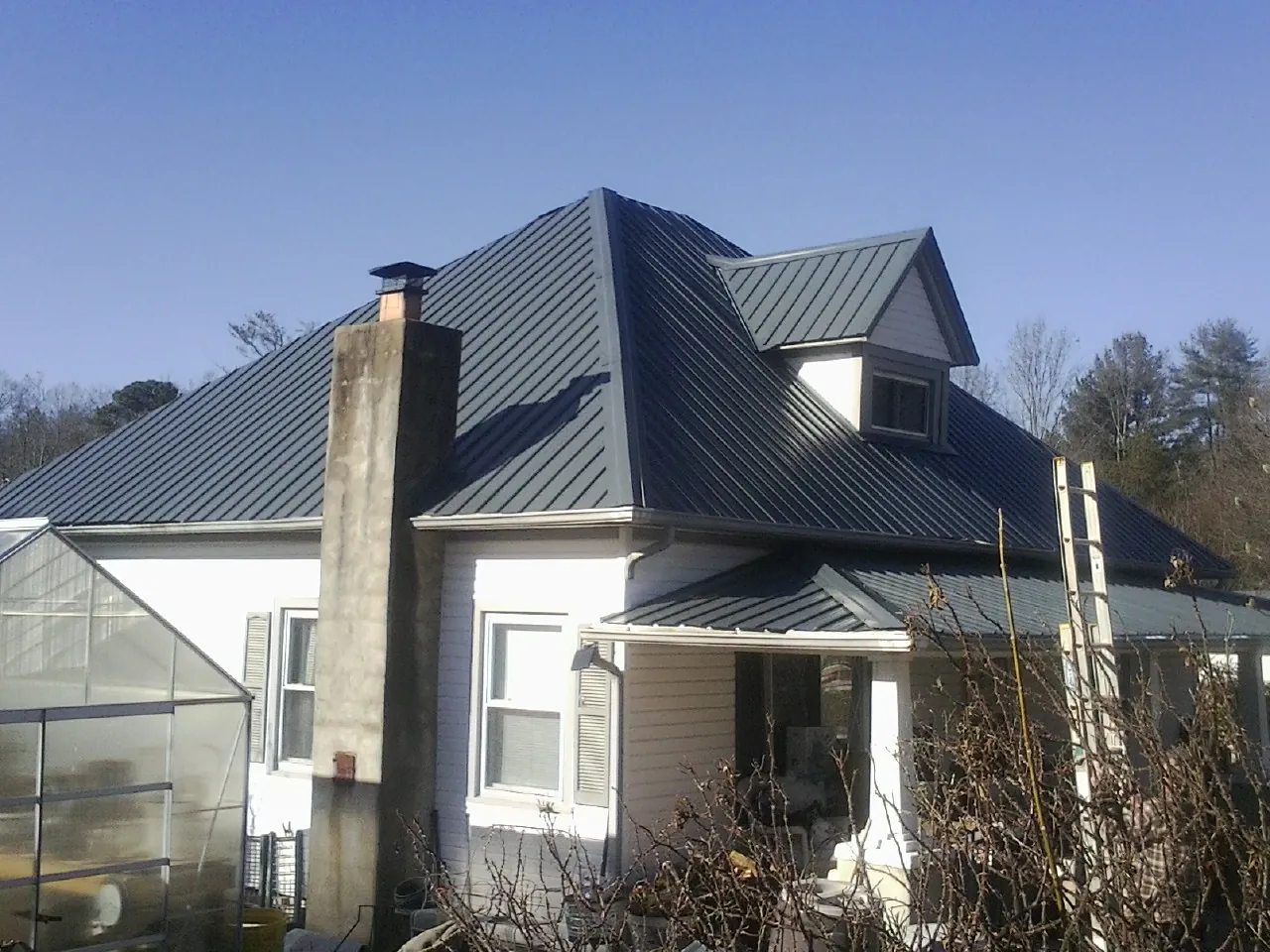 Dark blue standing seam metal roof on a white farmhouse with dormer — Slate & Tile Roof Repair by Roofing Brothers in Boonsboro