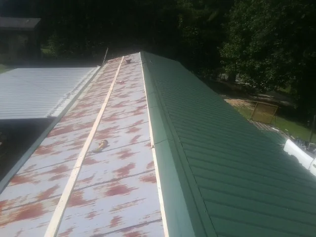 Old rusted panels beside newly installed green metal roofing — Wind Damage Roof Repair by Roofing Brothers in Boonsboro