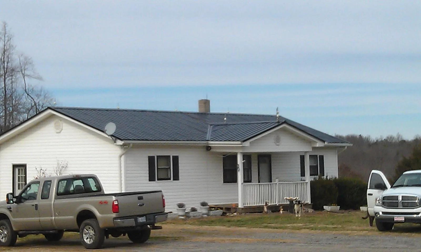 Finished dark metal roof on a white ranch home with work trucks parked in Boonsboro