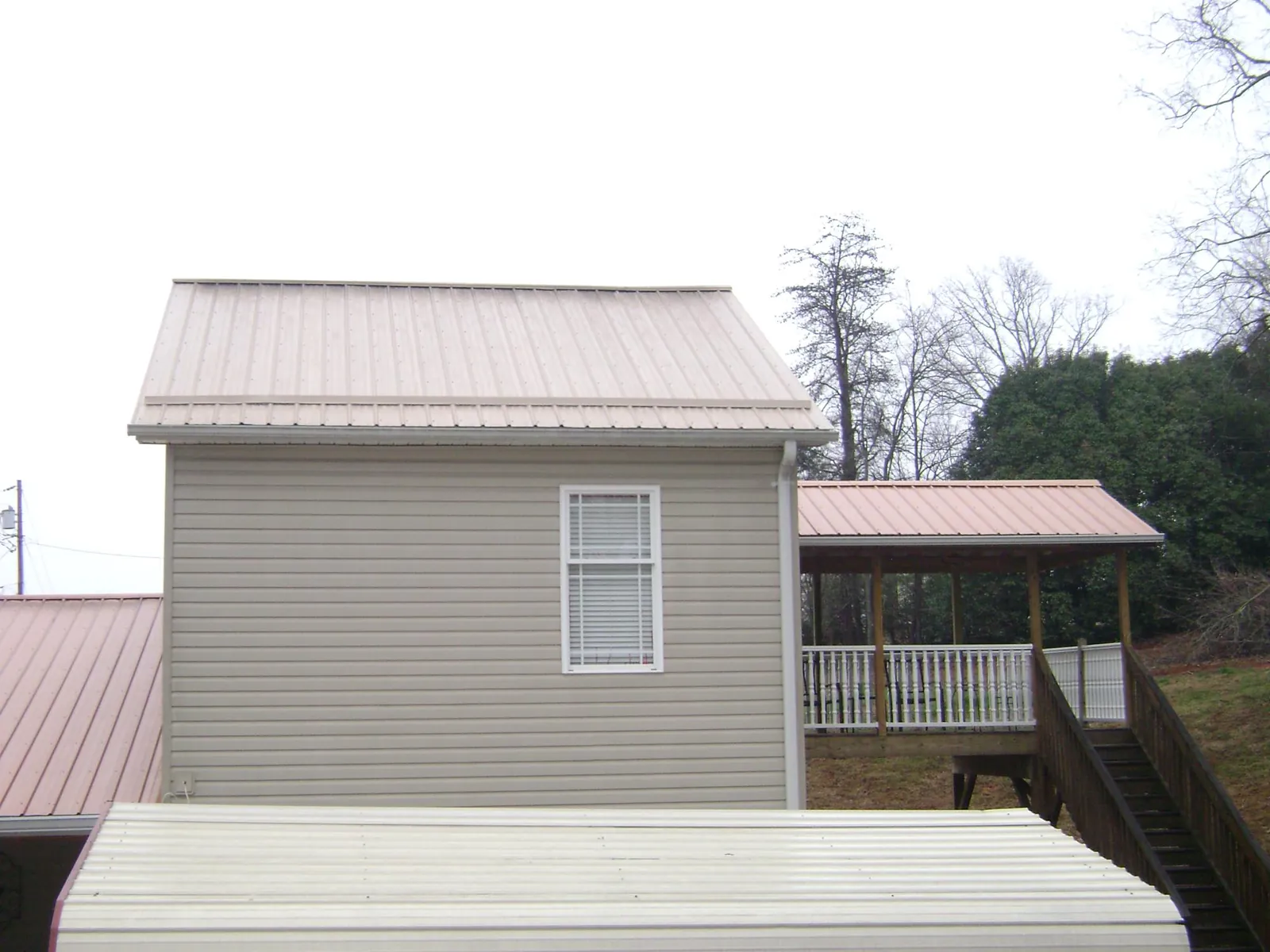 Tan metal roofs on a two story addition and attached porch, from a Roof Replacement job in Boonsboro