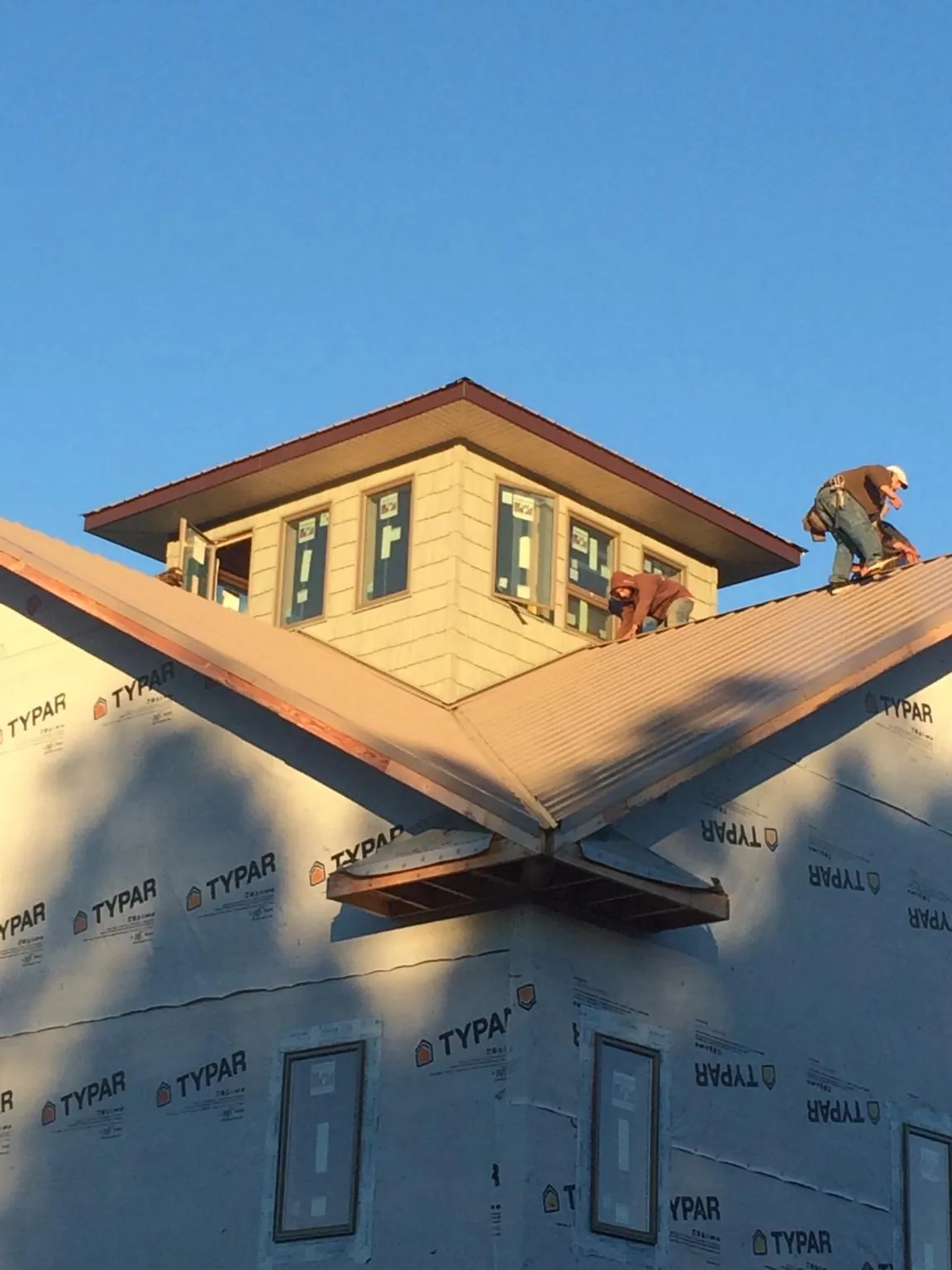 Roofers working around a rooftop cupola on a new metal roof at sunset — Roof Waterproofing in Boonsboro by Roofing Brothers